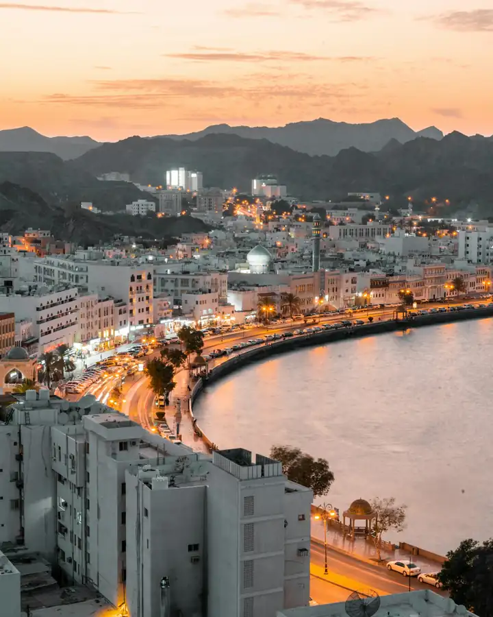 Muscat's coastline and city lights at dusk